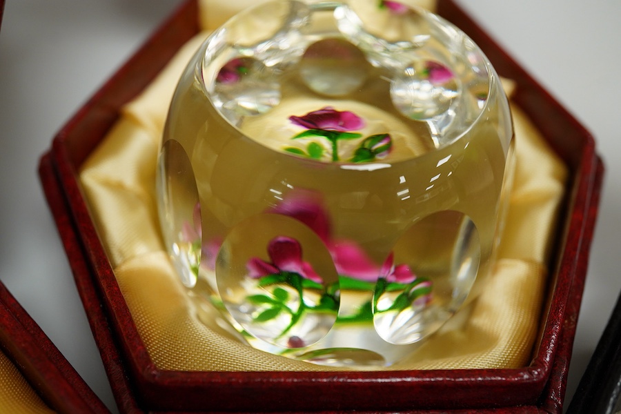 Two Perthshire lamp work glass paperweights, fruit weight, 52/350, rose and bud weight, 69/300 together with a John Deacons bouquet on a ruby base paperweight, edition of 101 (3)